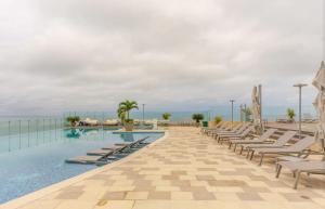 a swimming pool with lounge chairs and the ocean at Luxury Oceanfront Apartment Spiaggia 2BR 3BA Playa azul Cartagena in Cartagena de Indias