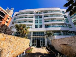 a tall white building with a courtyard in front of it at FLAT MANDAI Praia do Forte - Cabo Frio - RJ in Cabo Frio