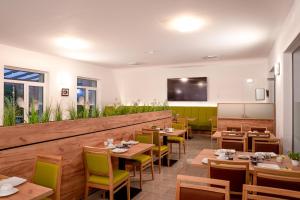 a restaurant with wooden tables and chairs and a flat screen tv at Hotel ANNA - Düsseldorf - Hilden in Hilden