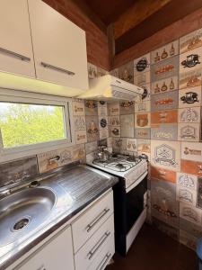 a small kitchen with a stove and a sink at Casas de campo Traslasierra in Villa Cura Brochero