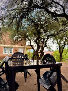 a black picnic table and chairs in front of a tree at Casas de campo Traslasierra in Villa Cura Brochero +21 photos