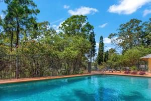 a swimming pool with a fence and trees at Villa in the Valley in Pokolbin