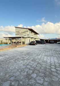 a building with cars parked in a parking lot at Pousada Oásis das Dunas in Santo Amaro