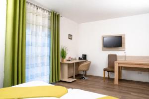 a bedroom with green curtains and a desk and a television at Hotel ANNA - Düsseldorf - Hilden in Hilden +16 photos