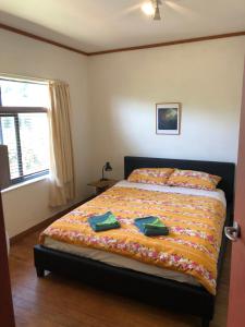 a bedroom with a bed with green napkins on it at Dragon's Den - self contained unit in Takaka