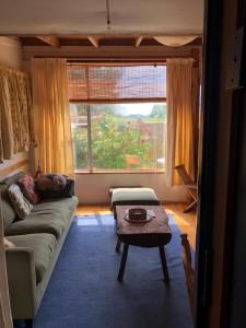 a living room with a couch and a table and a window at Dragon's Den - self contained unit in Takaka