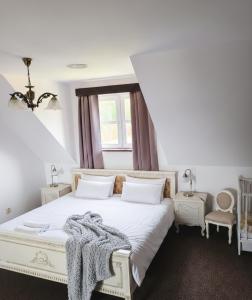 a bedroom with a white bed with a blanket on it at Mazurska Chata Rydzewo in Rydzewo