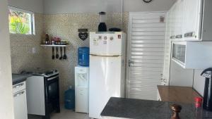 a kitchen with a white refrigerator and a stove at Casa Temporada Peter in Tutóia +3 photos