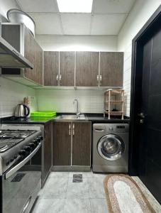 a kitchen with a sink and a washing machine at Entire Studio Apartment with King Bed in Ajman 