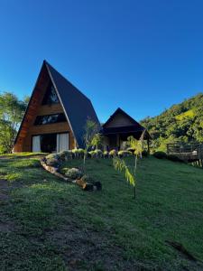 a house with a black roof on a green field at Chalé Rio Capetinga 01 in Anchieta