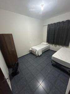a room with two beds and a cabinet in it at Casa BIG John 4 Bahia in Divinópolis