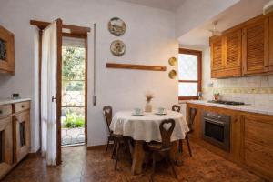 a kitchen with a table with chairs and a window at Villa summertime walking distance from the sea with garden in Fregene