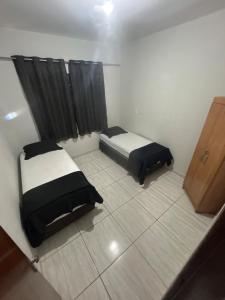 two beds in a small room with black curtains at Casa BIG John 5 Bahia in Divinópolis +7 photos