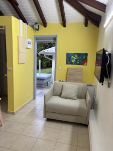 a living room with a couch and a yellow wall at Bungalow Cécilia in Petit-Bourg