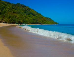 a line of waves on a beach with a mountain at H Boutique Blessed in Tela