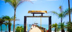 a boardwalk on a beach with palm trees and the ocean at H Boutique Blessed in Tela +2 photos