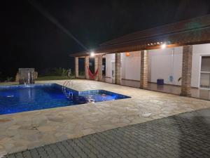 a swimming pool in a backyard at night at Chácara Lari & Sapão in Socorro