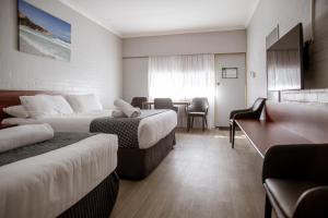 a hotel room with two beds and a desk at Bayview Motel in Esperance