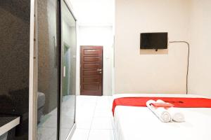 a small room with a bed and a tv on the wall at RedDoorz Syariah Near Jam Gadang Bukit tinggi 2 in Bukittinggi