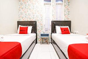 two twin beds in a room with red pillows at RedDoorz Syariah Near Jam Gadang Bukit tinggi 2 in Bukittinggi