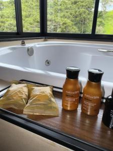 a bathroom counter with two bottles of honey and a bath tub at Terra Alta Chalé in Gonçalves