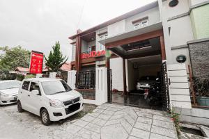 a white car parked in front of a building at RedDoorz Syariah Near Jam Gadang Bukit tinggi 2 in Bukittinggi