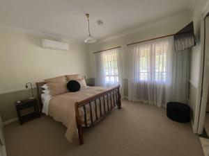 ein Schlafzimmer mit einem Bett und zwei Fenstern in der Unterkunft Loggers Rest B&B in Stanthorpe