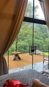a bedroom with a view of a wooden deck at Chalé Rio Capetinga 02 in Anchieta