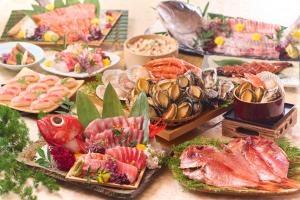 a table filled with different types of seafood and meats at Ooedo Onsen Monogatari Premium Ito Hotel New Okabe in Ito +7 photos