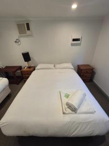 a bedroom with a white bed with a book on it at Otways Tourist Park in Gellibrand +105 photos
