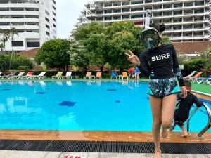 a woman wearing a gas mask standing in front of a swimming pool at PATONG TOWER Residence Apartments 2026 in Patong Beach