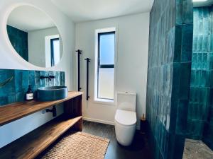 a bathroom with a sink and a toilet and a mirror at The Modern Alpine Oasis - Mountain Views - Rainfall Shower - Perfect for Couples in Wanaka +7 photos