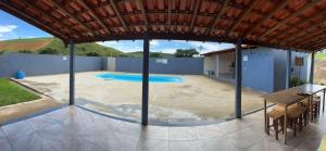 a covered patio with a table and a swimming pool at Rancho do Tomate in São Roque de Minas