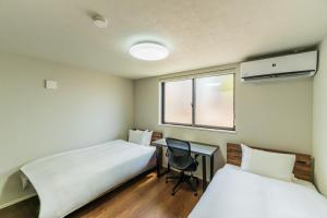 two beds in a room with a desk and a window at Flower Base Botan in Fukuoka