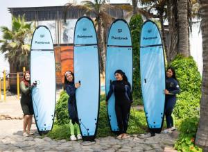 four women standing in front of four surfboards at Pointbreak Surf Camp in Huanchaco