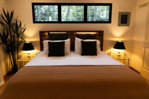 a bedroom with a bed with pillows and two lamps at The Nest! in Cannonvale