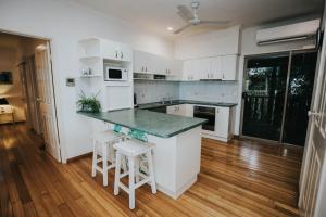 a kitchen with white cabinets and a counter with stools at The Nest! in Cannonvale