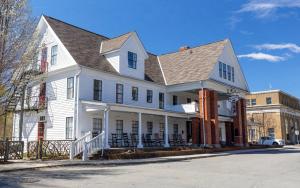 a white house with a gambrel roof on a street at The NuWray Hotel & Carriage House in Burnsville