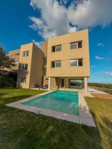 a building with a swimming pool in front of a house at VIENTOS apartments in Villa Gesell