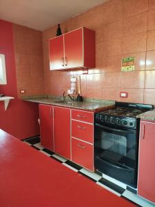 a red kitchen with red cabinets and a black oven at El Pedregullo in Neuquén