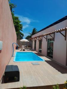 a swimming pool next to a building with a patio at Pousada Flor da Barra in Maragogi