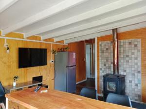 a kitchen with a table and a refrigerator and a stove at Cabaña El ulmo in Quelalmahue