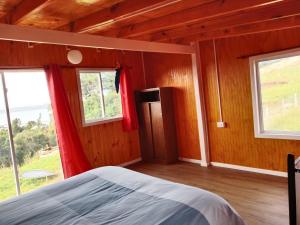 a bedroom with a bed and two windows at Cabaña El ulmo in Quelalmahue