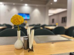 a yellow flower in a white vase on a table at Serene Forest Resort in Nainital