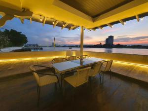 a table and chairs on a deck with a view of the water at Chao phraya riverfront house Baan Rimphraya in Bangkok +90 photos