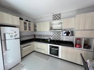 a kitchen with a white refrigerator and white appliances at Casa inteira com Piscina - 3 Quartos - Área Gourmet - 5 min da Praia in Prado +9 photos