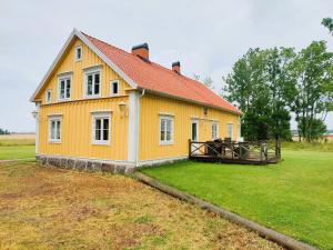 a yellow house with a red roof on a field at 4 star holiday home in ÖDESHÖG in Ödeshög