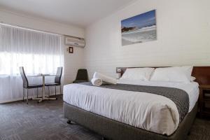 a hotel room with a bed and a table with a tableablish at Bayview Motel in Esperance