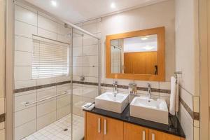 a bathroom with two sinks and a shower and a mirror at Manhattan Escape Suite By Ezey Tours in Cape Town +46 photos