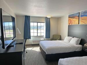 a hotel room with a bed and a desk with a television at Clarion Pointe Winslow I-40 in Winslow +53 photos